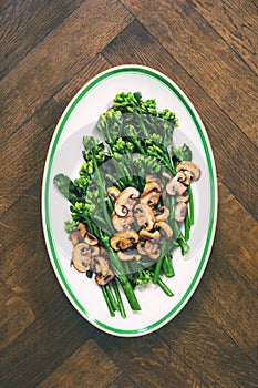 Stir-fried broccolini with mushrooms in an oval dish, top down view