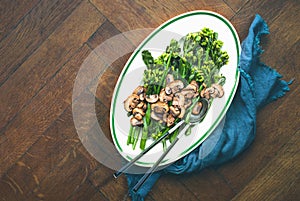 Stir-fried broccolini with mushrooms in an oval dish, top down view