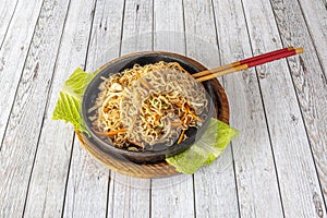 Stir-fried curly Chinese noodles with fried vegetables and chicken hole metal bowl and with chopsticks