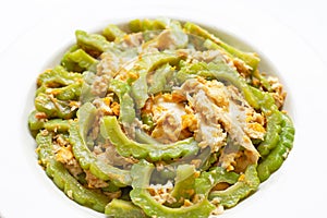 Stir-fried egg with bitter melon on a white dish on white