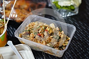 Stir-fried glass noodles in a clear plastic food container on a black rattan tab photo
