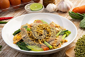 Stir fried instant Japanese style vegetable noodles with Soy Sauce and chicken breast in white plate.