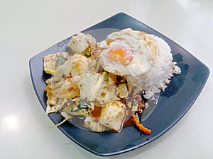 Stir Fried mixed vegetables with Roasted Chili Paste , fried egg & Thai jasmine rice on black dish. Vegetarian Food, healthy