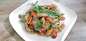 Stir-fried mussels with basil on a white plate