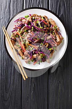 Stir-fried pork meat moo shu with vegetables close-up in a plate. Vertical top view