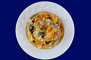 Stir fried pumpkin with egg and basil isolated on blue background