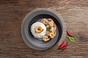 Stir-fried shrimp with basil and eggs Thai street food arranged on black plates Spicy Thai food placed on a wooden table. Top view