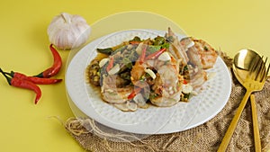 Stir-fried shrimp with chilli with garlic and chilli and spoon and fork with yellow background