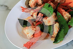 Stir Fried Shrimp or prawns with Chili and kaffir lime leaves on white plate.