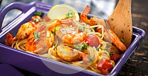 Stir-fried spaghetti with grilled shrimps and tomatoes - Italian fusion food style.