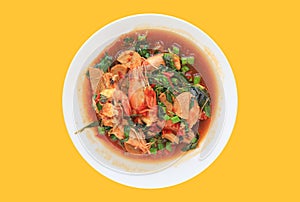 Stir-fried spicy Prawn and Pork sausage with basil leaf on circle ceramic plate isolated on yellow background. Hot and Spicy thai