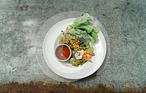 Stir-Fried Spicy Shanghai Noodle with Seafood. White plate of spicy fried Shanghai noodles with basil leafs and hot chili with