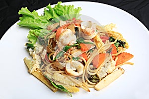 Stir Fried Spicy spaghetti with mixed seafood and herb on white plate