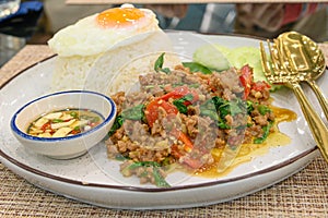 Stir fried Thai basil with minced pork and a fried egg on white plate