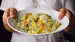Stir-Fried Vegetables With Rice Noodles on a dish with lady hands. Chinese dish. Vegetarian festival.