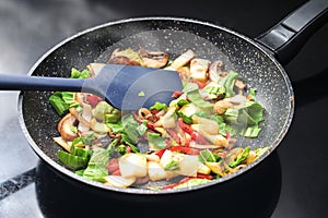 Stir-fried vegetables steaming in a frying pan, healthy vegetarian cooking with ingredients like bell pepper, mushroom, onions and