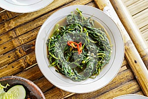 Stir-fried Water Spinach, Morning Glory, Stir-fried Kale, tumis kangkung served on a white plate