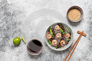 Stir fry buckwheat soba noodles with shrimps and vegetables in a bowl. Gray concrete grunge background. Asian
