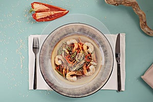 Stir fry noodles with vegetables and shrimps in pan. Slate background. Top view.