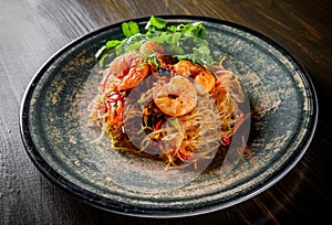 Stir fry noodles with vegetables and shrimps in plate on wooden table