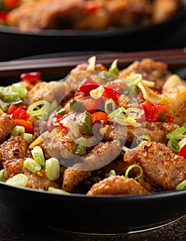 Stir fry salt and pepper pork loin with herbs in black bowl. Asian food