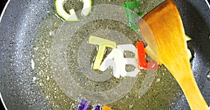 Stir-frying mixed alphabet letters, word Vegetables