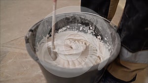 Mixing concrete plaster with electric mixer. Stir the solution in a bucket
