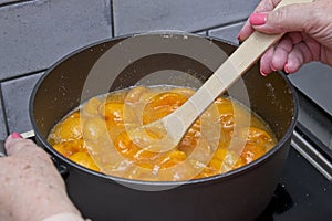 Stirring the apricot and sugar mixture in a saucepan while heating slowly