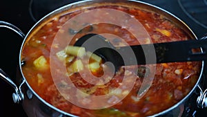 Stirring boiling soup in a saucepan close-up. Traditional Russian delicious meat soup Solyanka