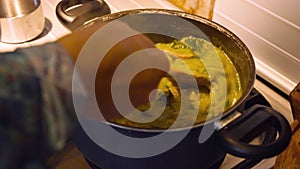 Stirring a Bubbling hot green gravy sauce with chicken and spinach with a wooden spoon