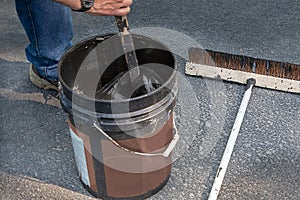 Stirring can of asphalt before pouring on driveway