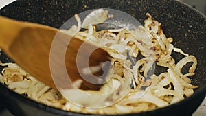 Stirring chopped onion is fried in a pan in vegetable oil, sea is added to it.