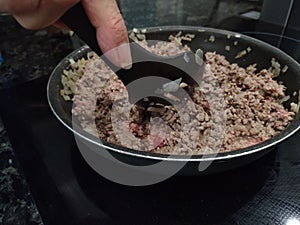Stirring Found Beef With a Plastic Slotted Spoon