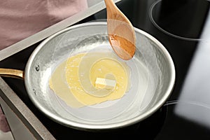 Stirring melted butter on frying pan in kitchen