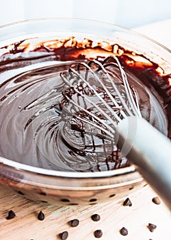 Stirring melted chocolate chips in bowl up-close on wood table