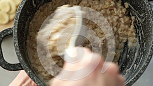 Stirring oatmeal porridge in cooking pan