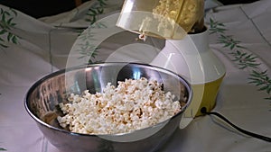 stirring popcorn with a spoon close-up in an iron bowl preparing popcorn for an evening movie viewing