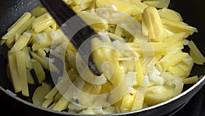 Stirring potatoes fried with onions in a frying pan