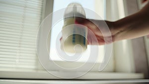 Stirring and shaking a bottle of milk baby food against the background of a window. Preparing infant formula. Copy space