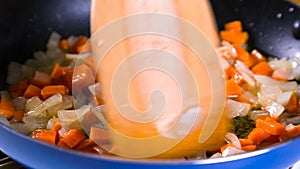 Stirring the sliced carrot and white onion on frying pan