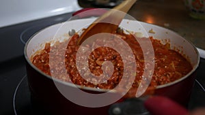 Stirring Tomato Sauce with Chicken in a pan over stove top