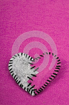 Stitched broken felt heart on a on pink background