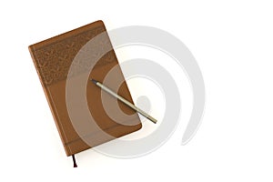 A stitched leather notebook with patterns on a brown cover and a gray pencil, isolated on a white table