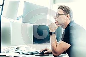 Stock broker trading online watching charts and data analyses on multiple computer screens.