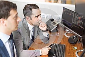 Stock brokers looking at computer screens, trading online.