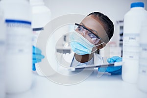 Stock check tablet, chemical bottle and black woman scientist with mask at pharmaceutical lab. Research, label reading