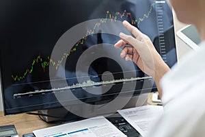 Stock exchange trader Analyzing Graphs chart or data On Multiple Screens in office