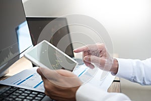 Stock exchange trader Analyzing Graphs chart or data On Multiple Screens in office