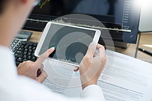 Stock exchange trader Analyzing Graphs chart or data On Multiple Screens in office