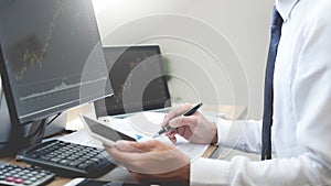 Stock exchange trader Analyzing Graphs chart or data On Multiple Screens in office